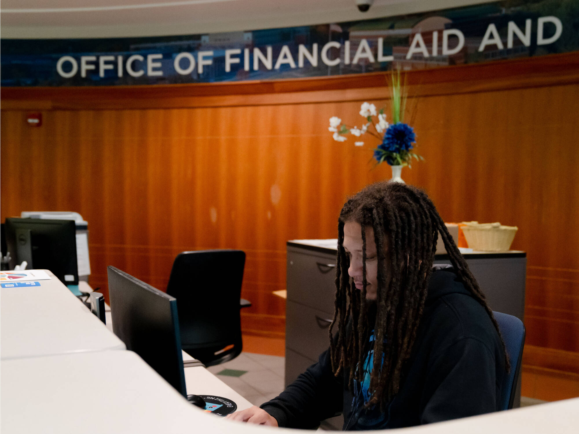 person sitting at desk in the office of financial aid and scholarships